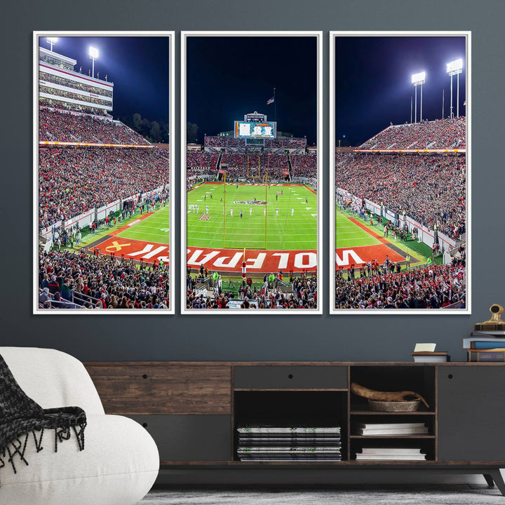 A NC State Wolfpack Football Team print of Carter-Finley Stadium at night features WOLFPACK illuminated brightly in the end zone grass.