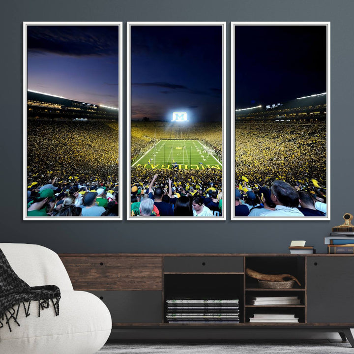 The wall art features a glowing M in this Michigan Wolverines Football Team Ann Arbor Stadium Canvas Print.