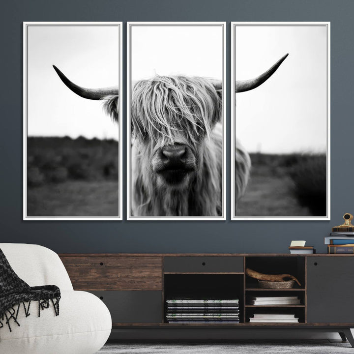 The Highland Cow Wall Art, a black and white farmhouse decor piece showcased as a triptych canvas print, graces a dark wall with its long-haired Scottish Highland cattle art print exuding rustic barn aesthetic.