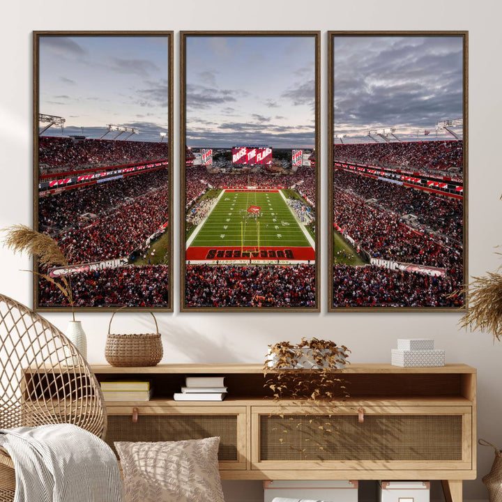 The wall art captures a stunning scene of Raymond James Stadium bathed in the warm hues of sunset. The sky, filled with clouds, provides a dramatic contrast to the vibrant lighting on the field, encapsulating the dynamic energy of a football game.