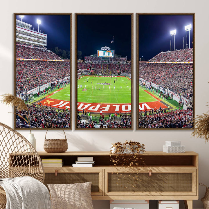 A NC State Wolfpack Football Team print of Carter-Finley Stadium at night features WOLFPACK illuminated brightly in the end zone grass.