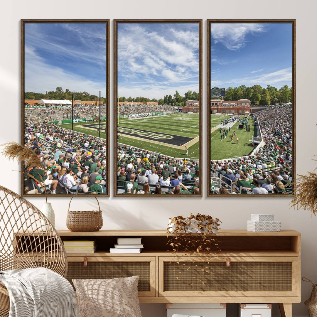 The University of Charlotte 49ers stadium print adds flair to a modern living room wall with its vibrant scene and clear sky.