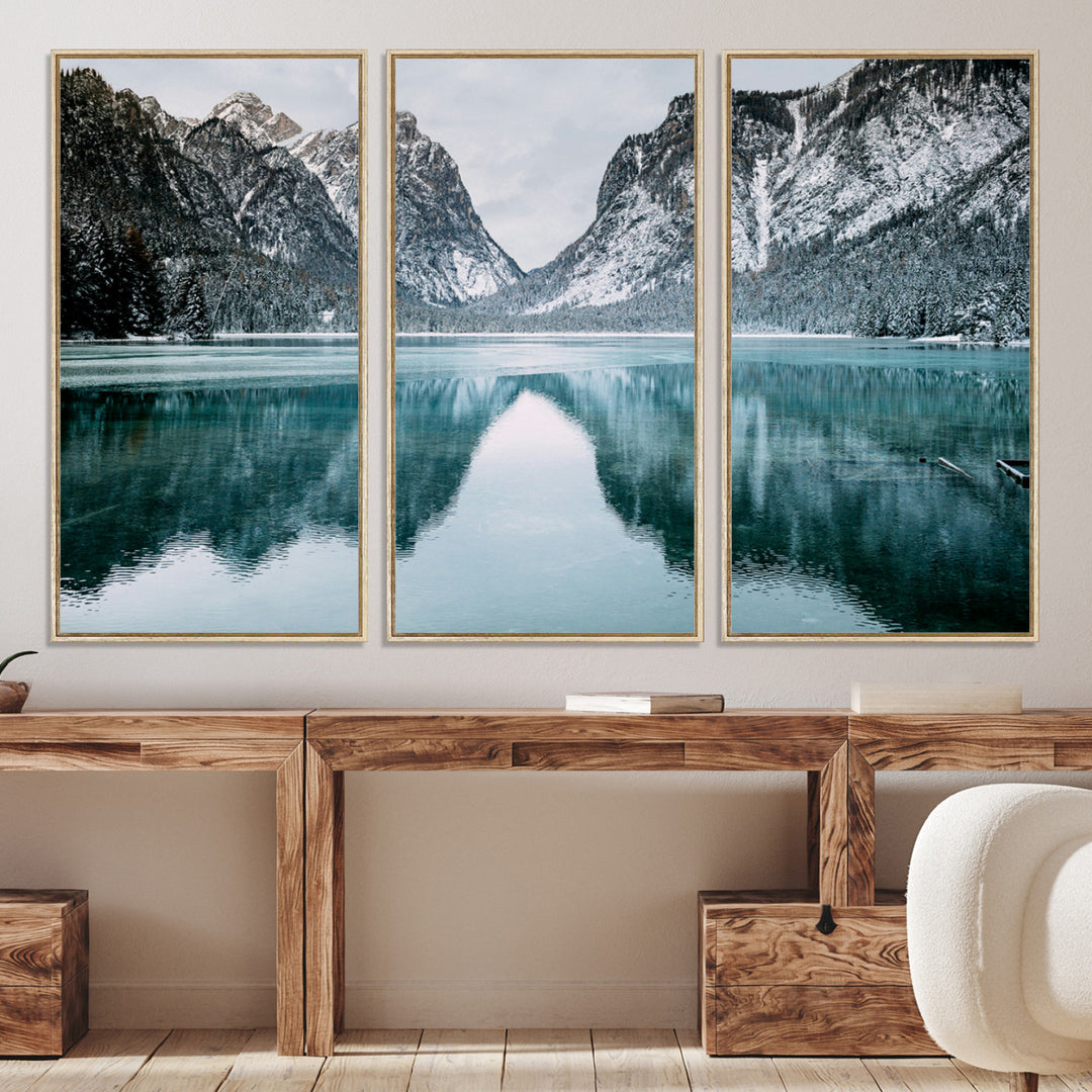 Crystal-clear alpine lake reflecting snow-covered mountains, surrounded by evergreen trees, creating a serene and tranquil winter landscape.