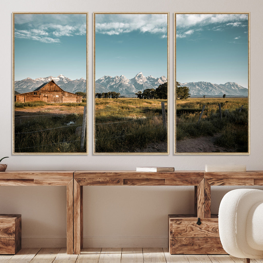 A rustic farmhouse with a wooden barn set against majestic mountain peaks under a soft blue sky, evoking peaceful countryside charm.