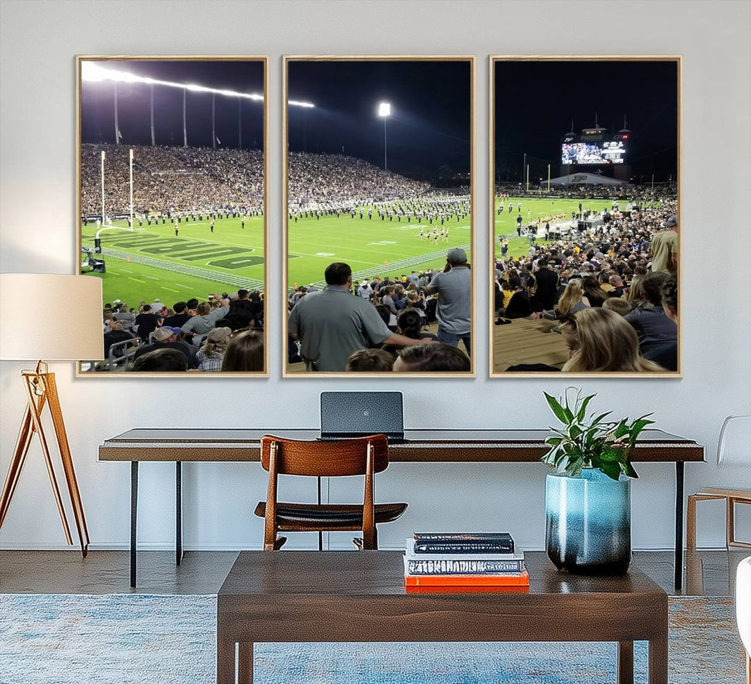 A painting depicting the Purdue Boilermakers football game at Ross-Ade Stadium is illuminated under gallery-quality lights.