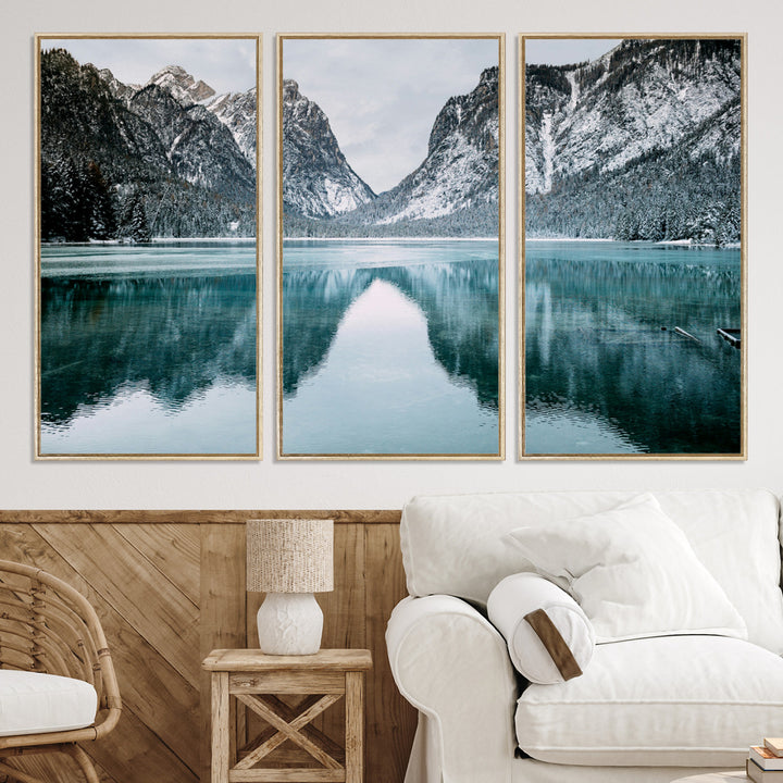 Crystal-clear alpine lake reflecting snow-covered mountains, surrounded by evergreen trees, creating a serene and tranquil winter landscape.