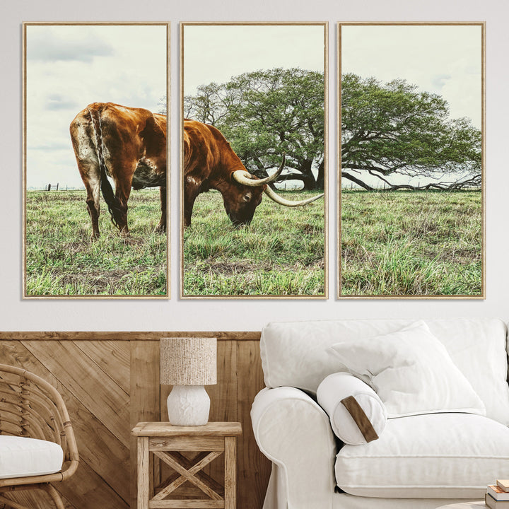A Texas Longhorn grazing in a green pasture with a large tree in the background, evoking a rustic Western and farmhouse aesthetic.