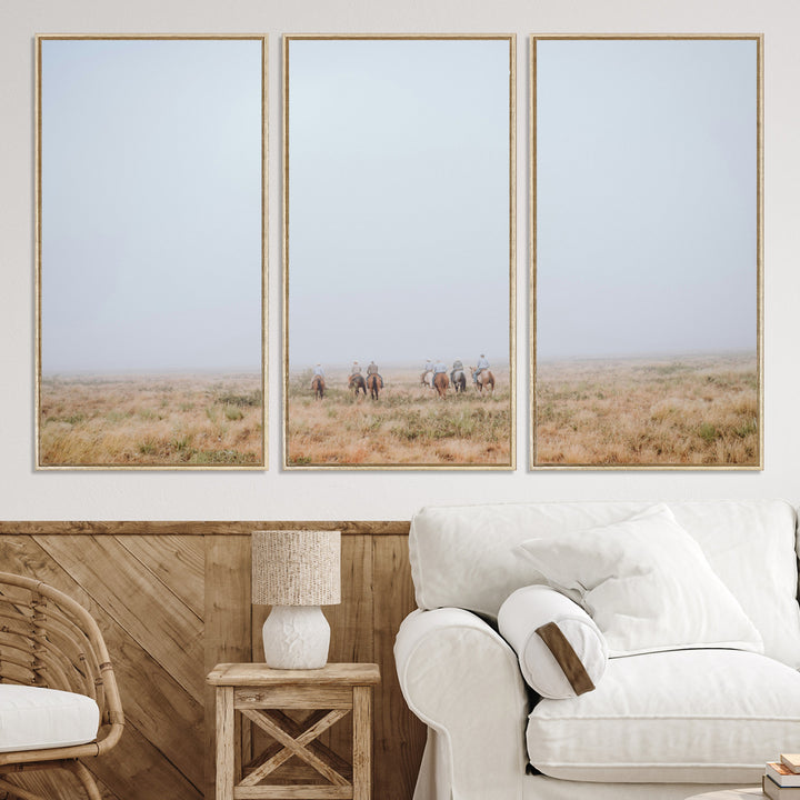 A group of horseback riders moving through a fog-shrouded field, evoking a calm Western scene with golden grasses and soft horizons.