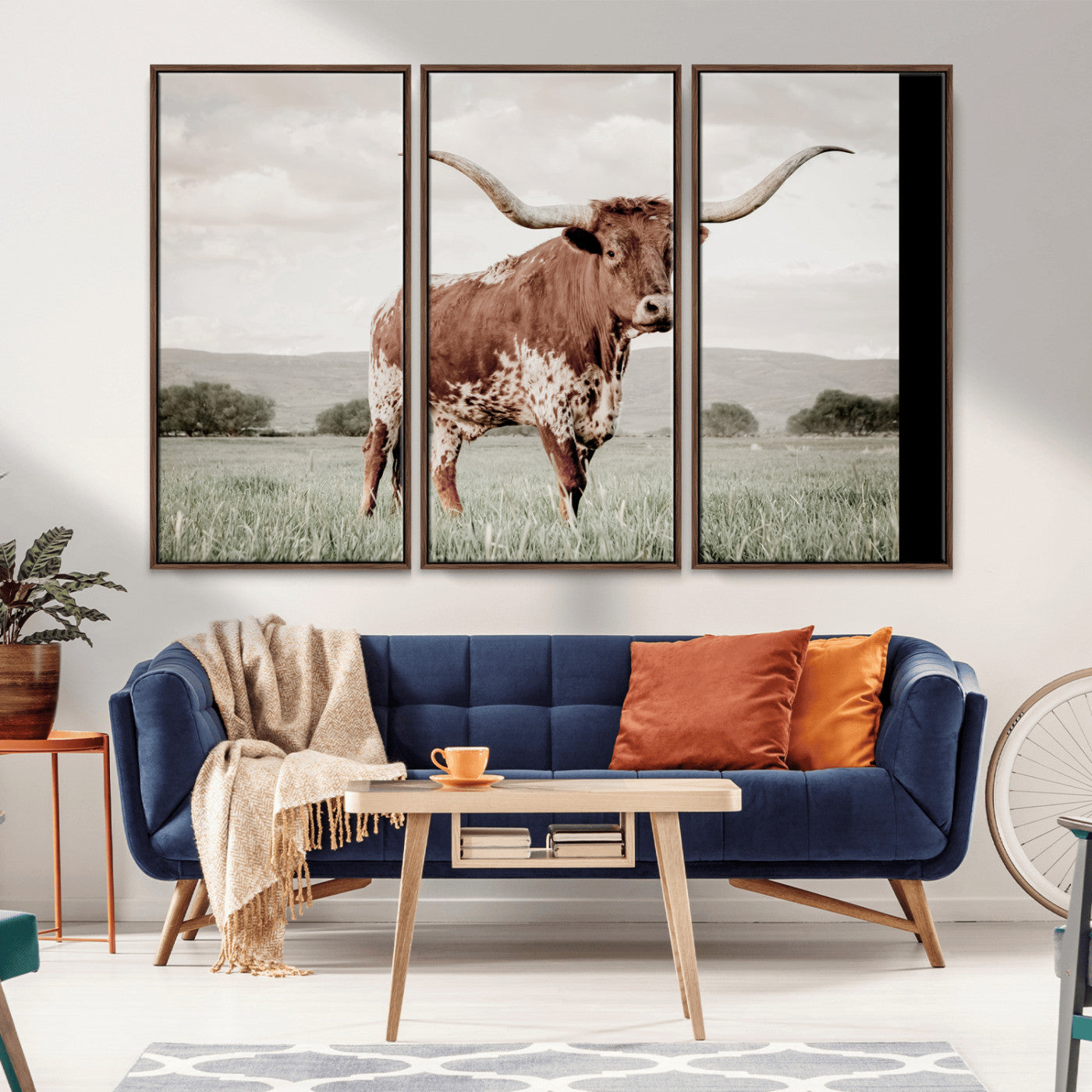Canvas of a Texas longhorn standing in a grassy field with mountains in the background, ideal for rustic or country-style western wall decor.