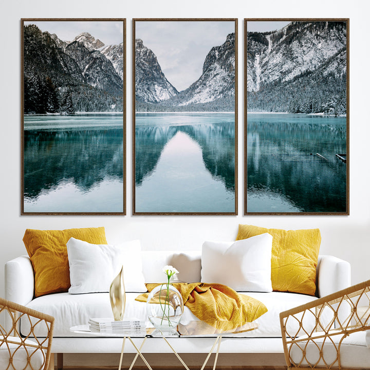 Crystal-clear alpine lake reflecting snow-covered mountains, surrounded by evergreen trees, creating a serene and tranquil winter landscape.