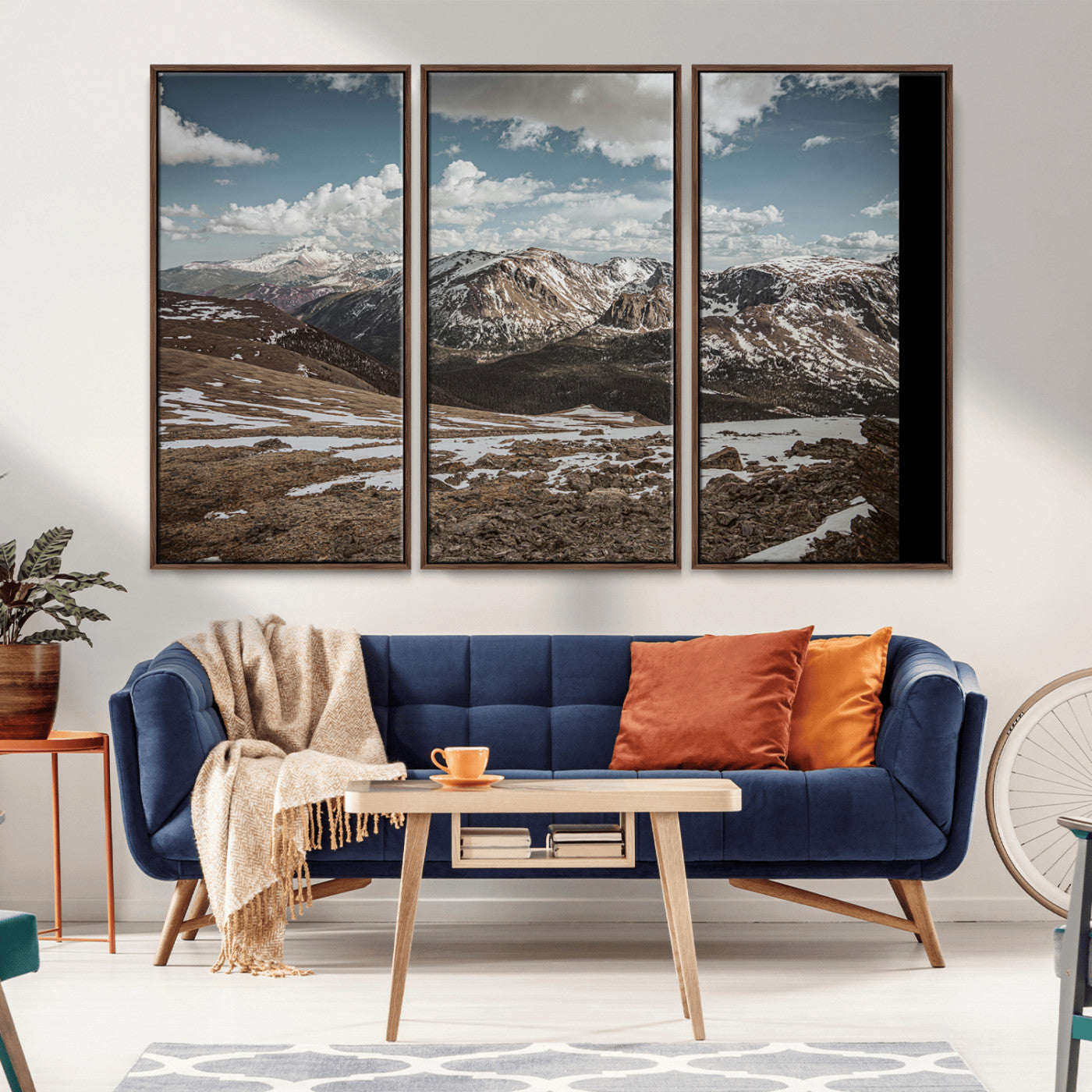 A breathtaking mountain landscape with rugged peaks, patches of snow, and dramatic clouds casting shadows over the vast alpine wilderness.