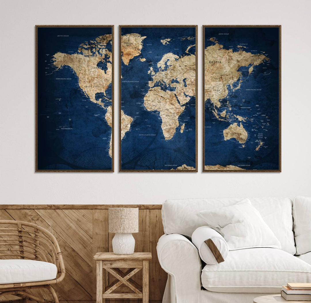 A large framed world map canvas print features beige landmasses set against a grunge-stained deep blue ocean background, creating an intriguing piece of wall art.