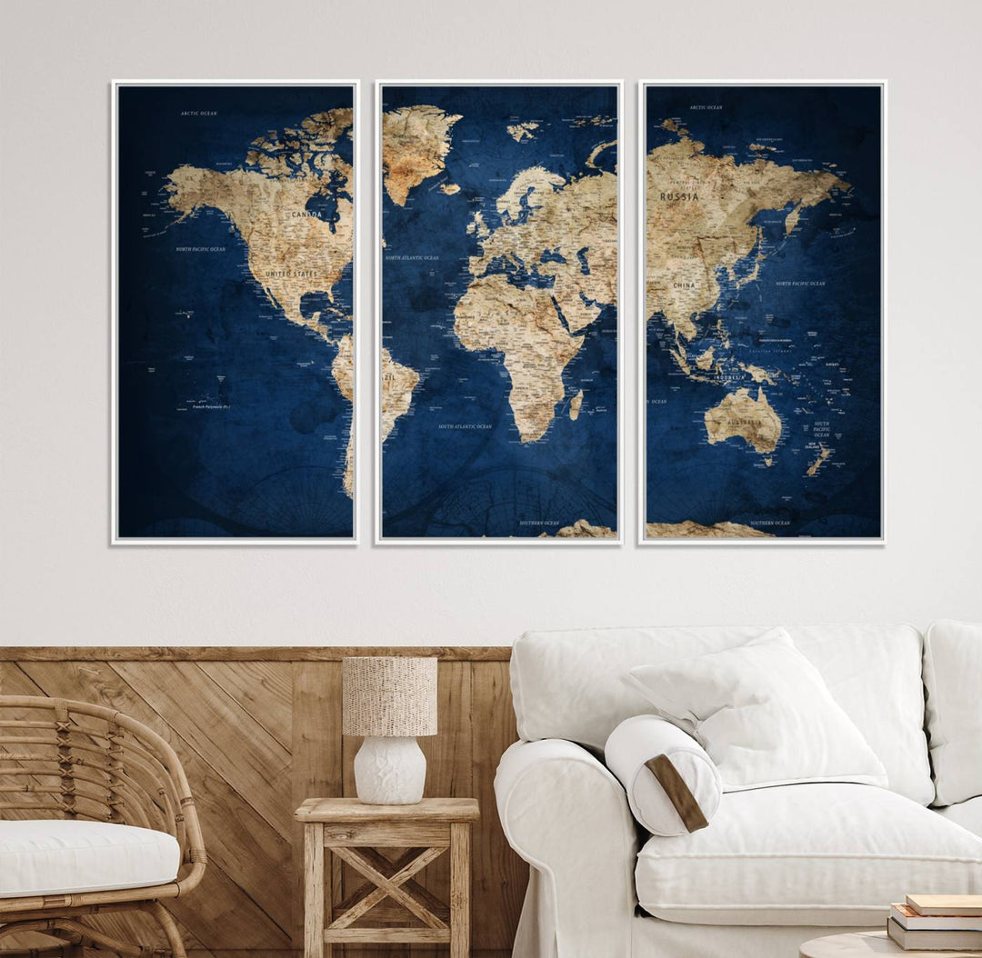 A large framed world map canvas print features beige landmasses set against a grunge-stained deep blue ocean background, creating an intriguing piece of wall art.