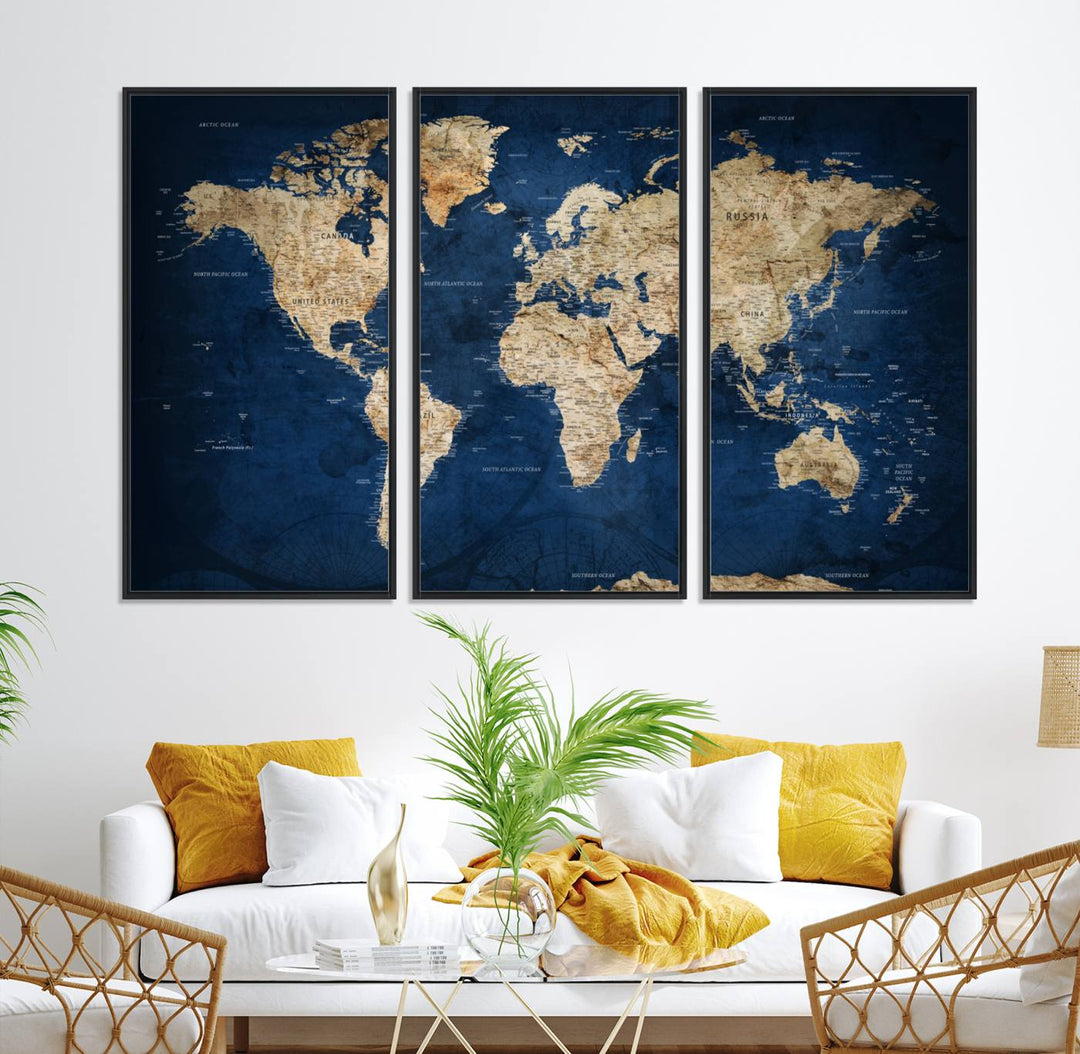 A large framed world map canvas print features beige landmasses set against a grunge-stained deep blue ocean background, creating an intriguing piece of wall art.