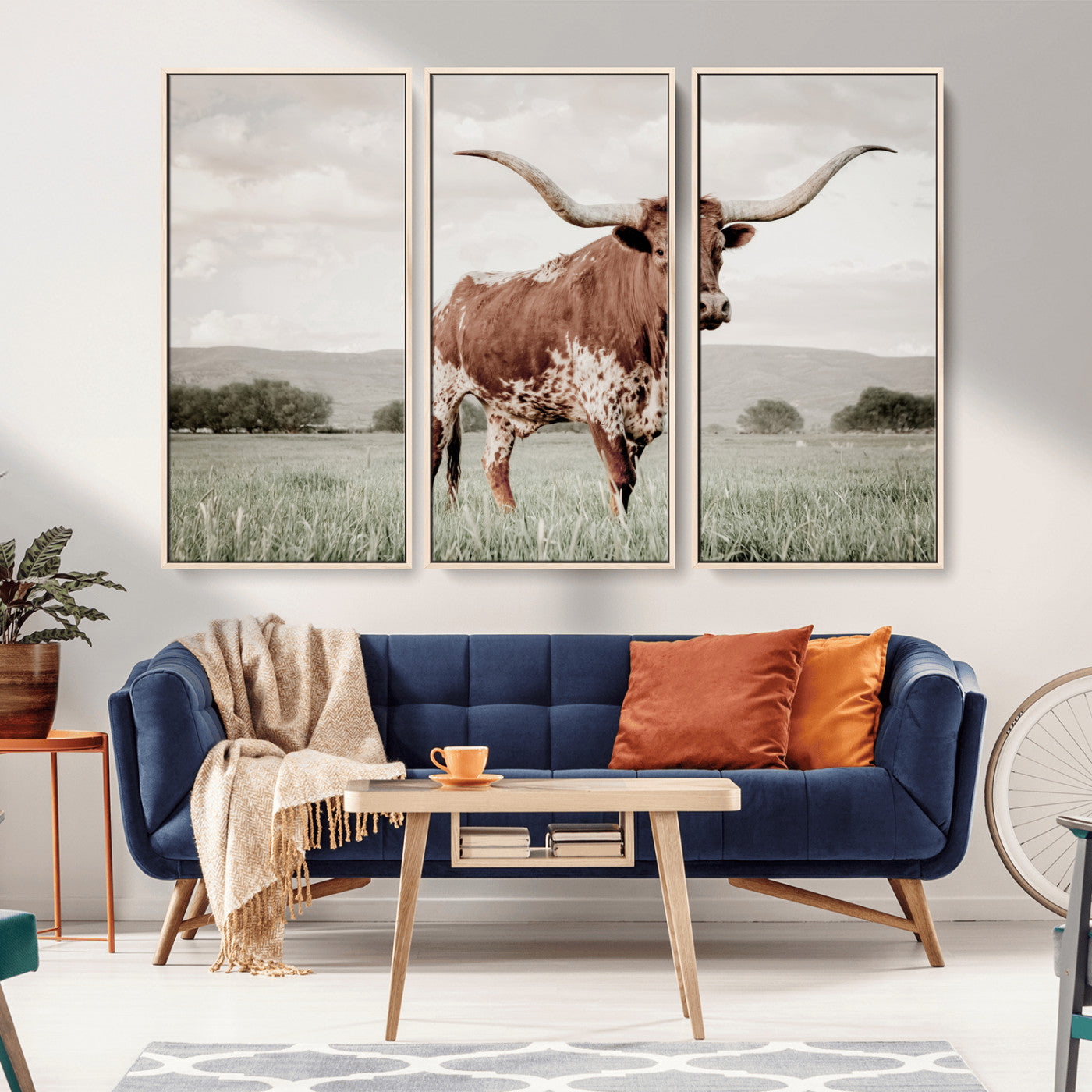 Canvas of a Texas longhorn standing in a grassy field with mountains in the background, ideal for rustic or country-style western wall decor.