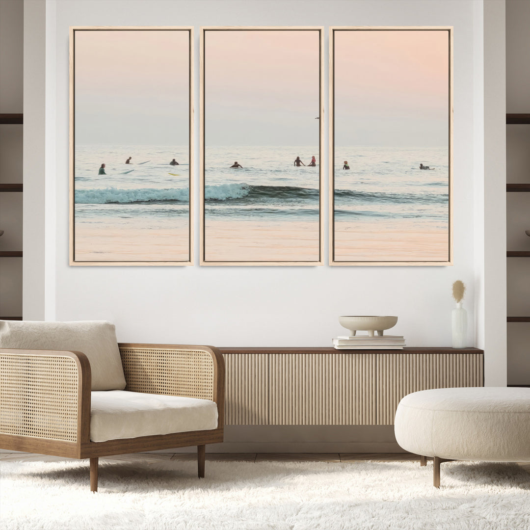 Dreamy photo of surfers waiting on soft pastel waves under a pink sunset sky, ideal for soft coastal minimalist or serene ocean-themed home decor.