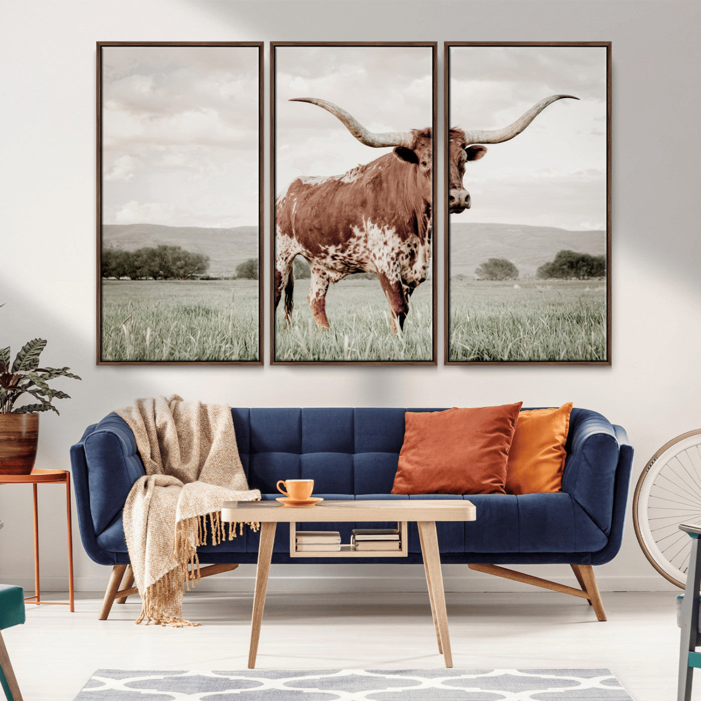 Canvas of a Texas longhorn standing in a grassy field with mountains in the background, ideal for rustic or country-style western wall decor.
