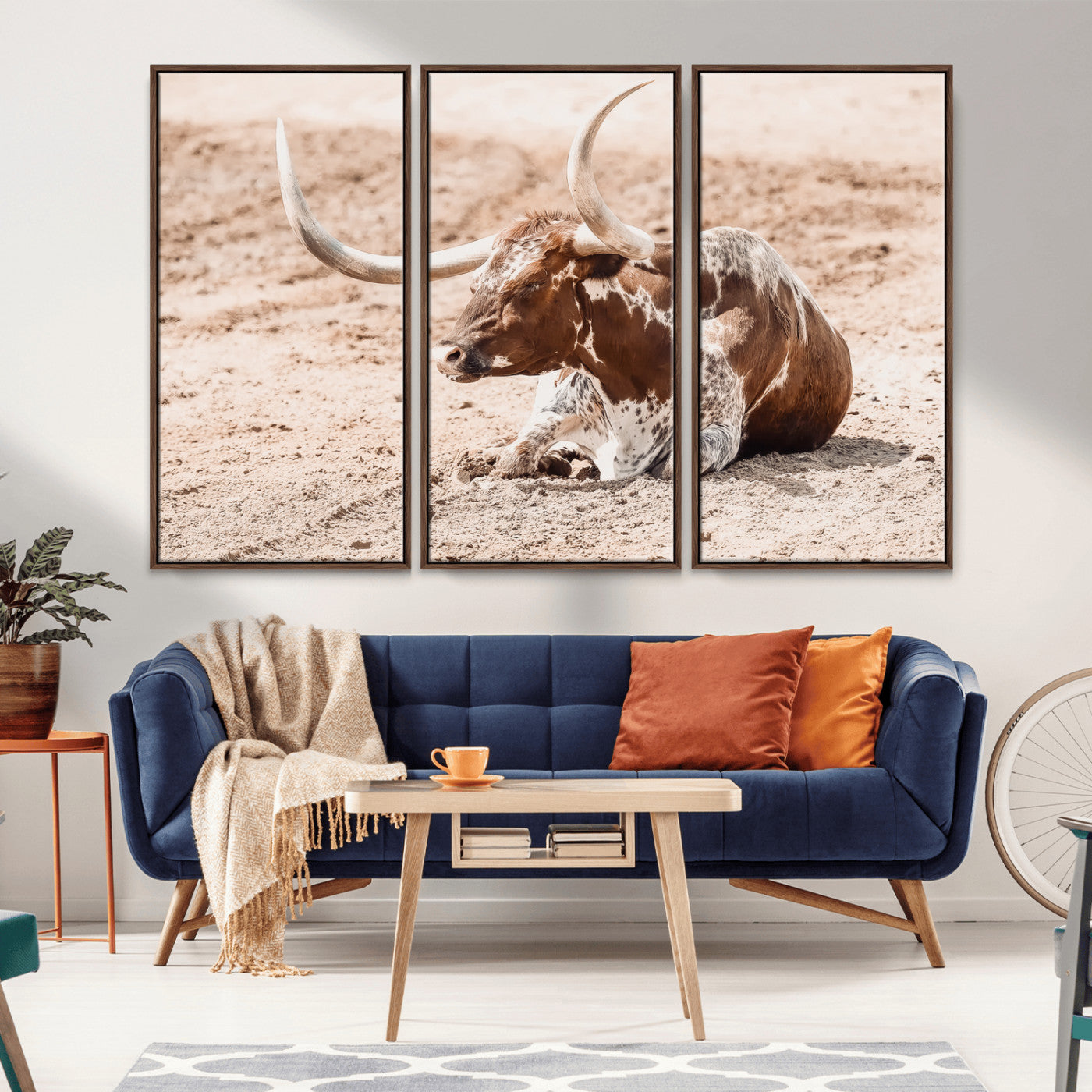 Texas Longhorn bull resting on dusty ground with warm tones, ideal for rustic western or farmhouse-themed wall decor.