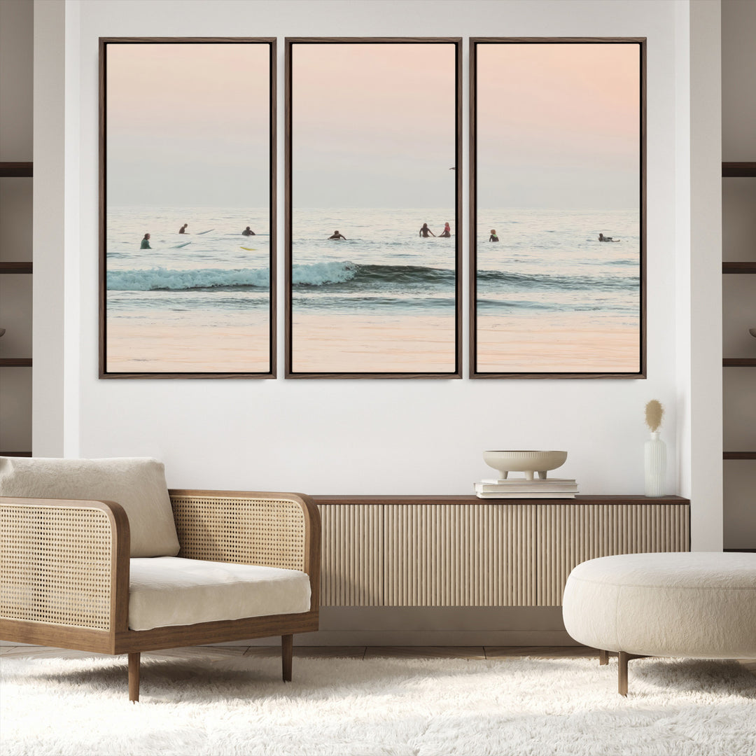 Dreamy photo of surfers waiting on soft pastel waves under a pink sunset sky, ideal for soft coastal minimalist or serene ocean-themed home decor.
