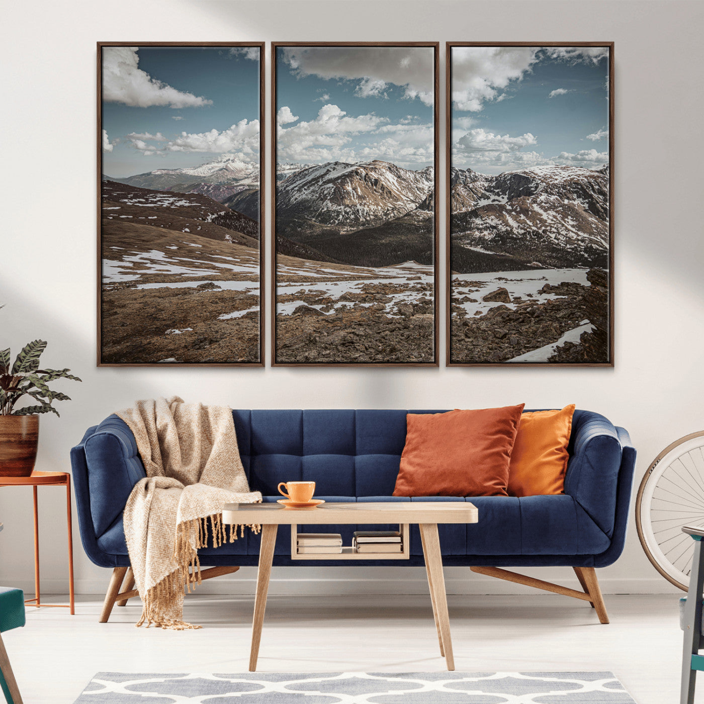 A breathtaking mountain landscape with rugged peaks, patches of snow, and dramatic clouds casting shadows over the vast alpine wilderness.