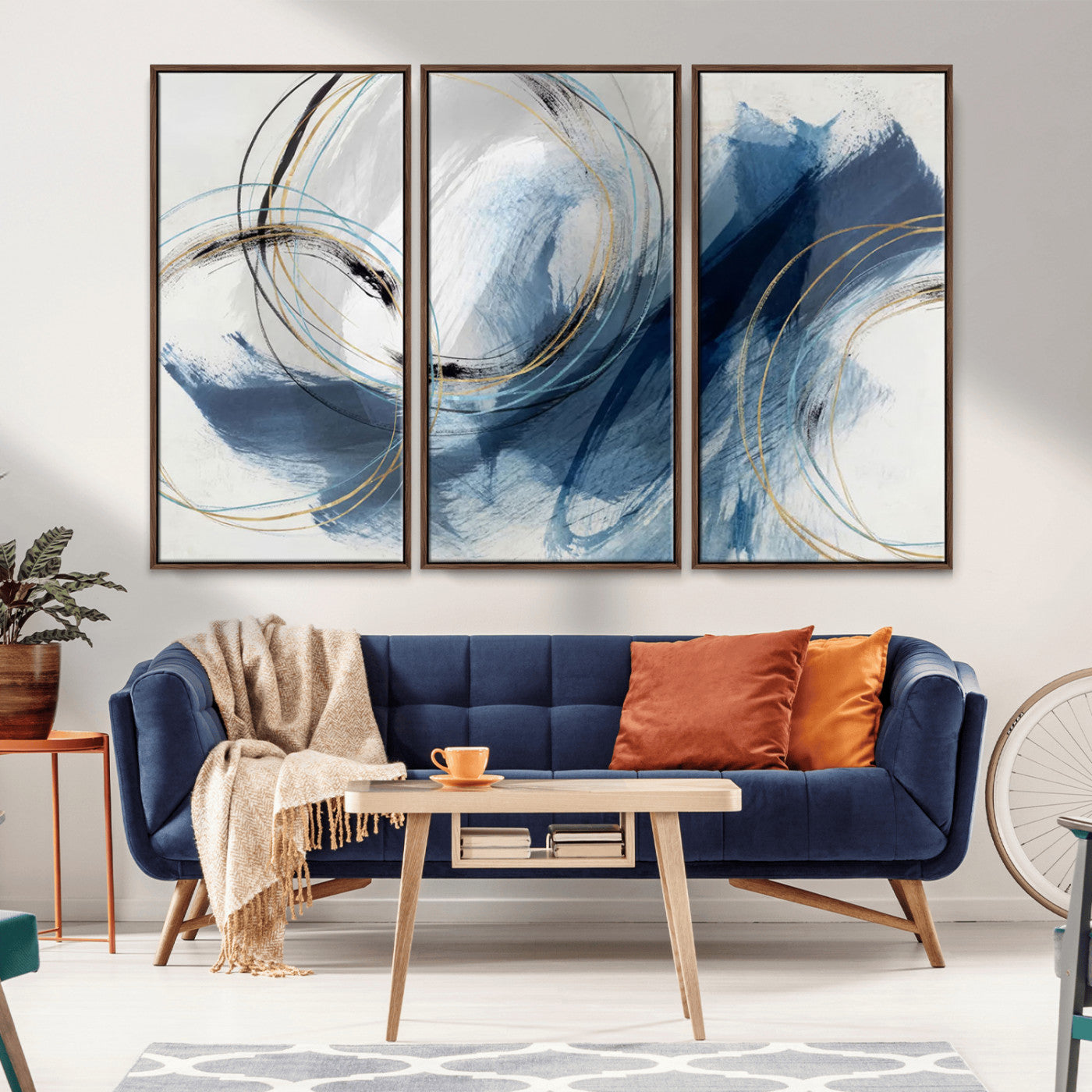 Abstract wall art featuring dynamic brush strokes in shades of blue and gray, overlaid with delicate circular line patterns in gold, black, and light blue on a white background.