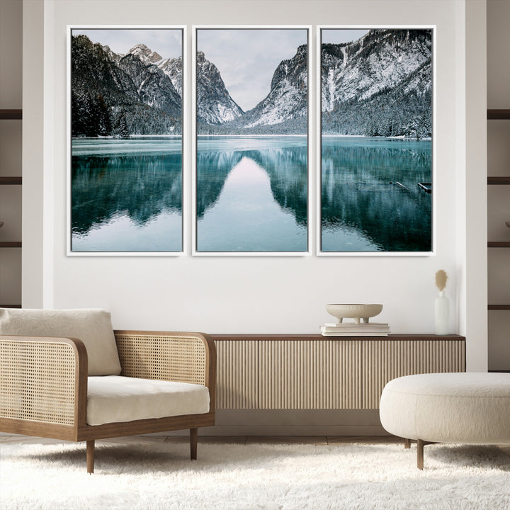 Crystal-clear alpine lake reflecting snow-covered mountains, surrounded by evergreen trees, creating a serene and tranquil winter landscape.
