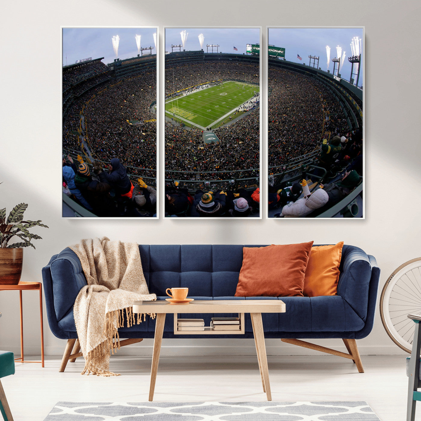 Wide fisheye view of a packed Lambeau Field stadium during an American football game. The crowd fills the stands, and fireworks are going off above the stadium lights. The scoreboard displays "Touchdown," and the field has "Packers" painted in the end zon