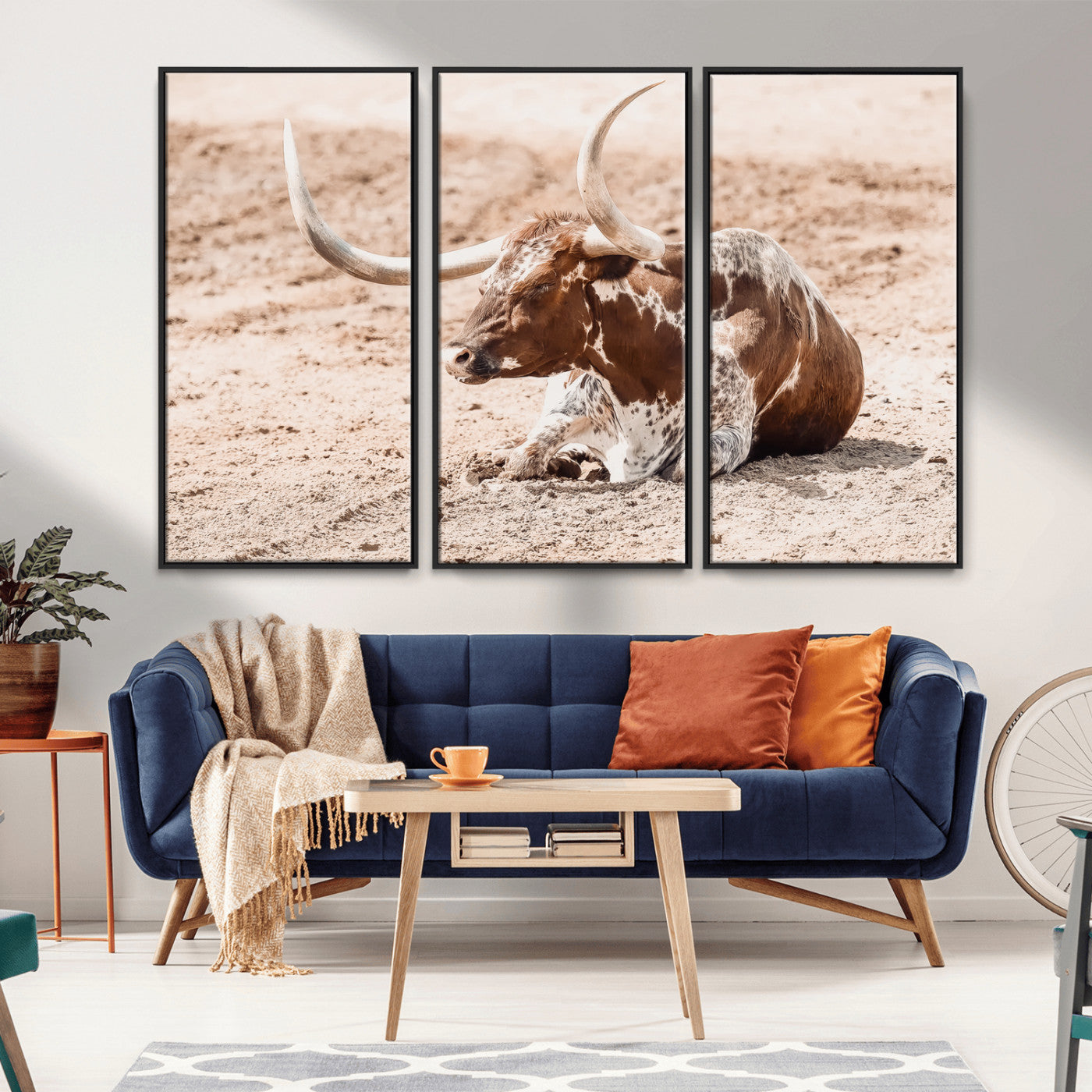 Texas Longhorn bull resting on dusty ground with warm tones, ideal for rustic western or farmhouse-themed wall decor.