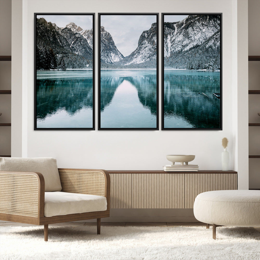 Crystal-clear alpine lake reflecting snow-covered mountains, surrounded by evergreen trees, creating a serene and tranquil winter landscape.