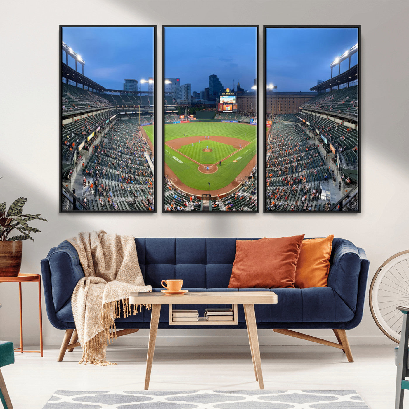 Wide panoramic view of a baseball stadium at dusk with players on the field, stadium lights illuminating the scene, and a sparse crowd of spectators in the stands.