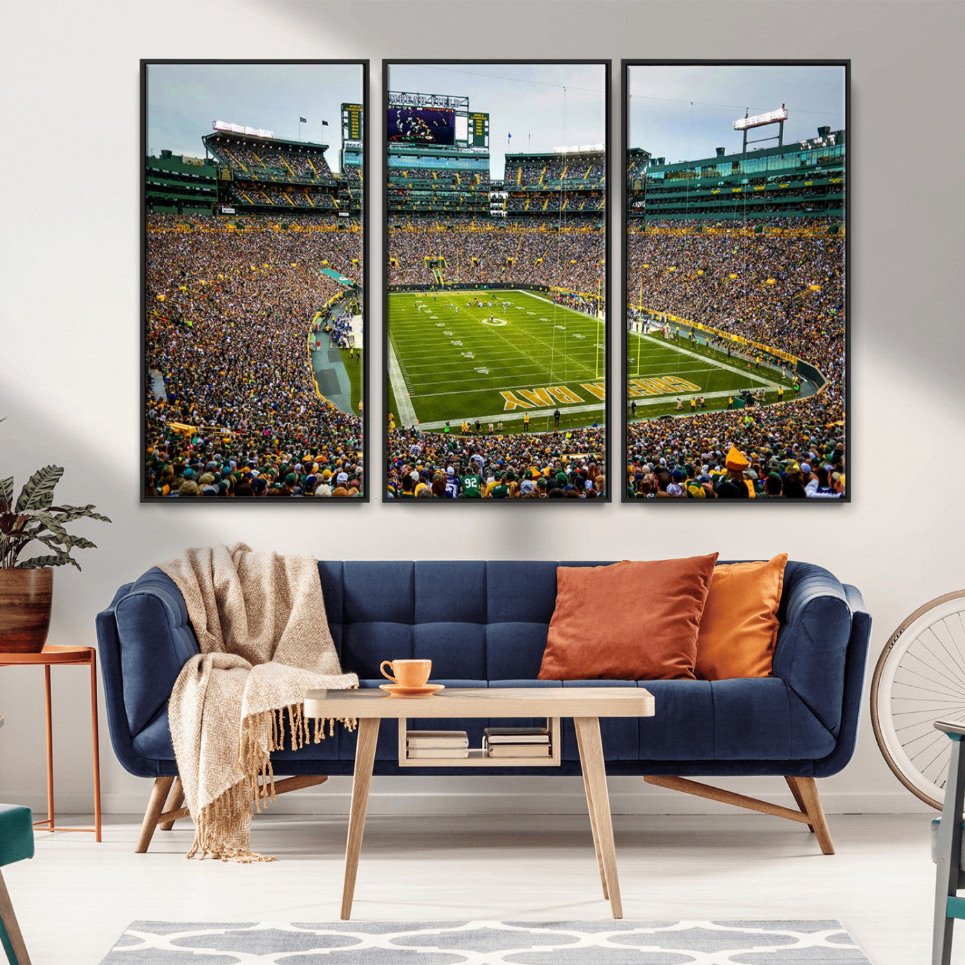 Packed football stadium with thousands of fans watching an American football game on a well-maintained field. The scoreboard displays "Lambeau Field," and players are lined up on the field. The stadium is surrounded by multiple tiers of seating filled wit