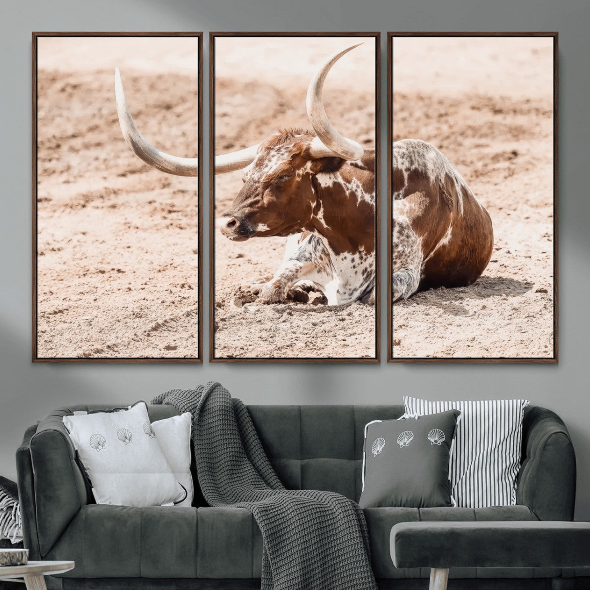 Texas Longhorn bull resting on dusty ground with warm tones, ideal for rustic western or farmhouse-themed wall decor.