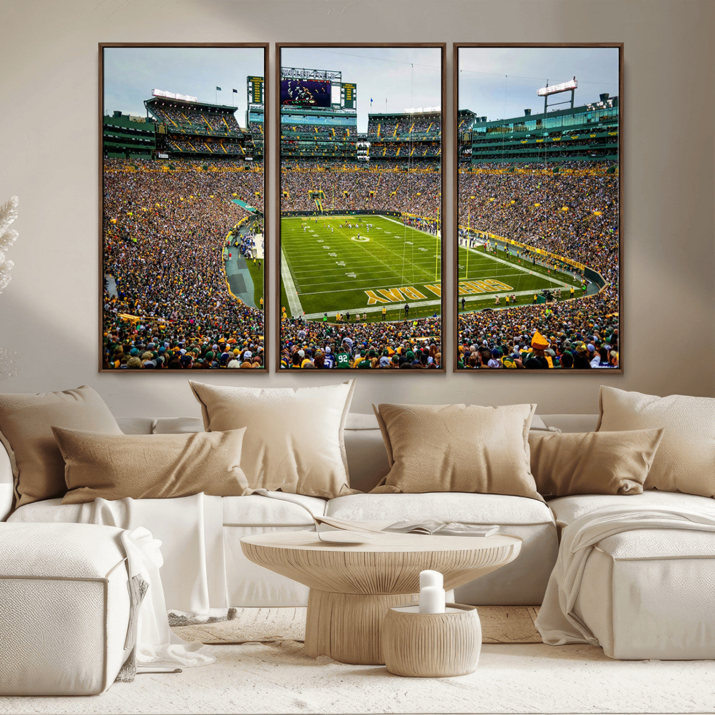 Packed football stadium with thousands of fans watching an American football game on a well-maintained field. The scoreboard displays "Lambeau Field," and players are lined up on the field. The stadium is surrounded by multiple tiers of seating filled wit