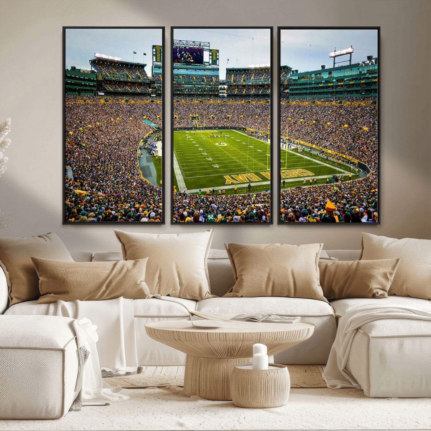 Packed football stadium with thousands of fans watching an American football game on a well-maintained field. The scoreboard displays "Lambeau Field," and players are lined up on the field. The stadium is surrounded by multiple tiers of seating filled wit