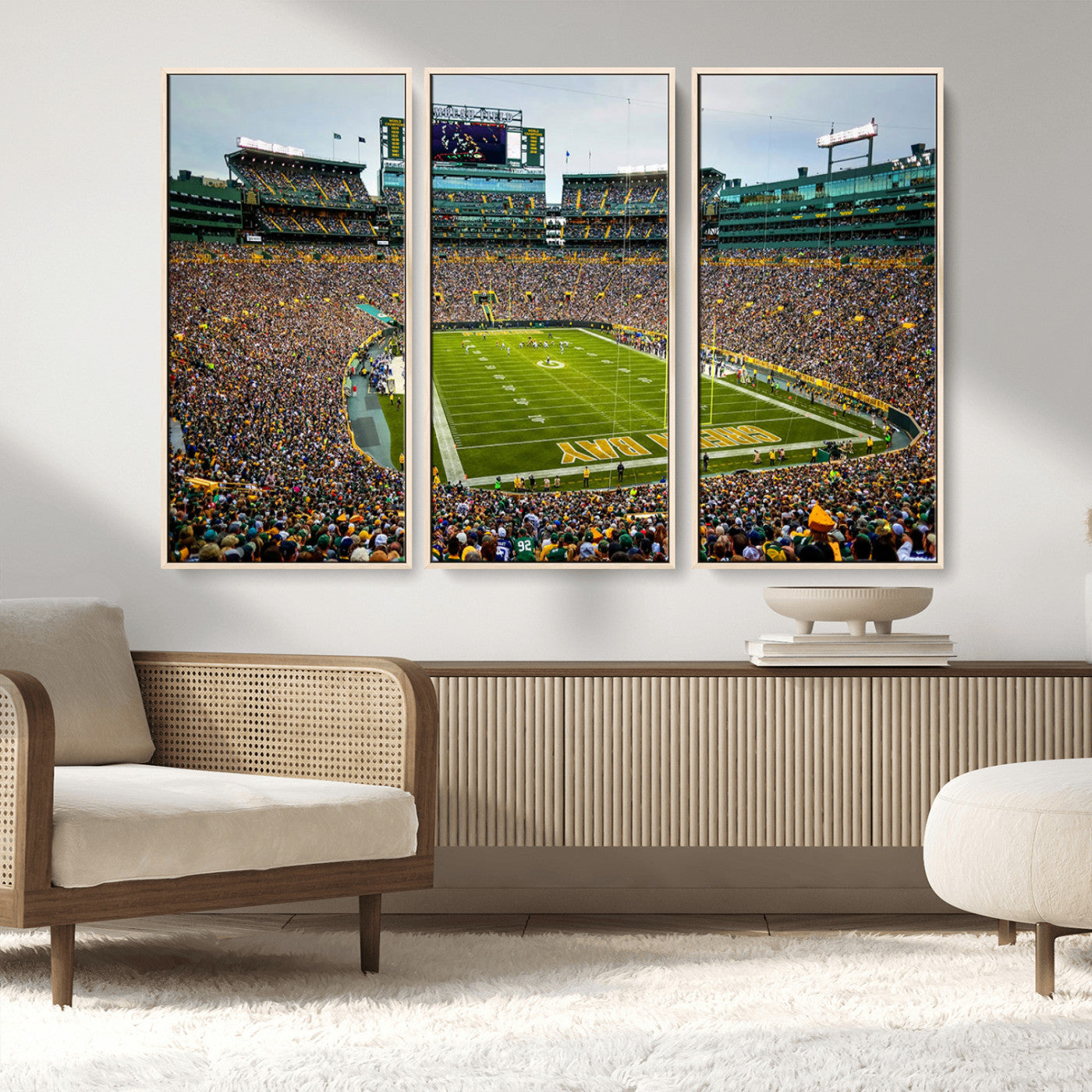 Packed football stadium with thousands of fans watching an American football game on a well-maintained field. The scoreboard displays "Lambeau Field," and players are lined up on the field. The stadium is surrounded by multiple tiers of seating filled wit