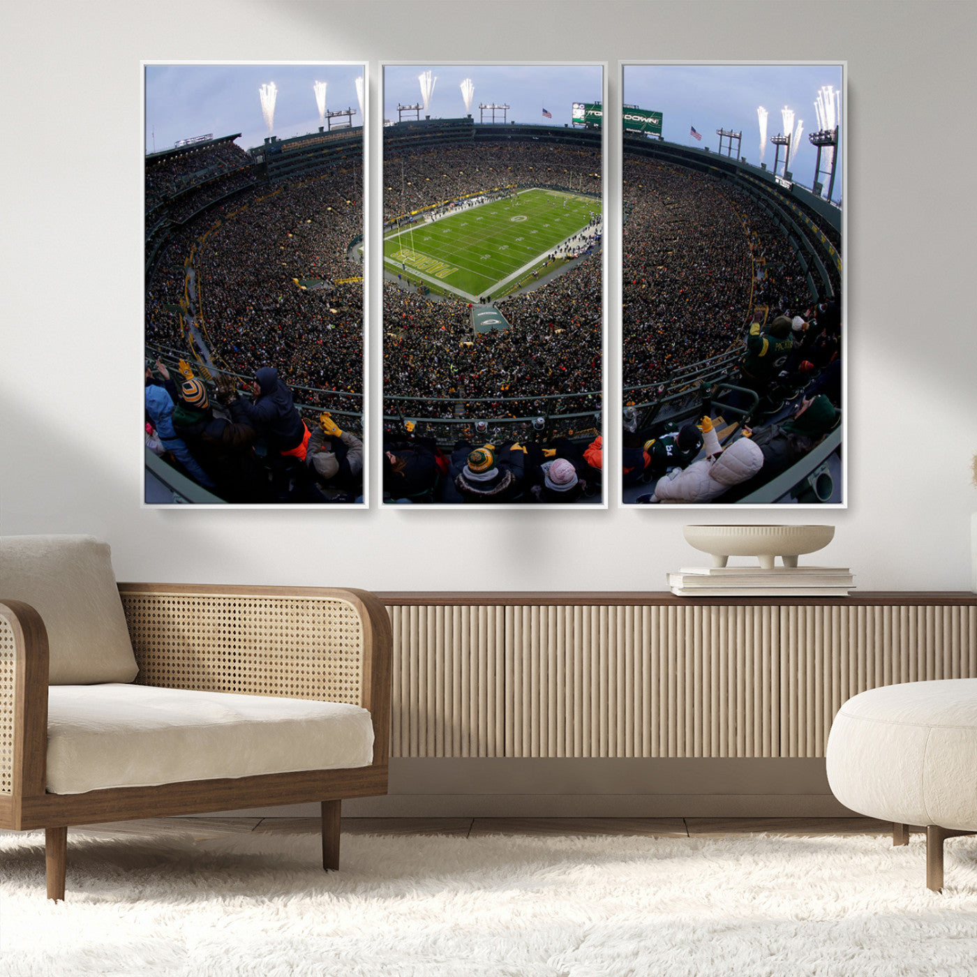 Wide fisheye view of a packed Lambeau Field stadium during an American football game. The crowd fills the stands, and fireworks are going off above the stadium lights. The scoreboard displays "Touchdown," and the field has "Packers" painted in the end zon
