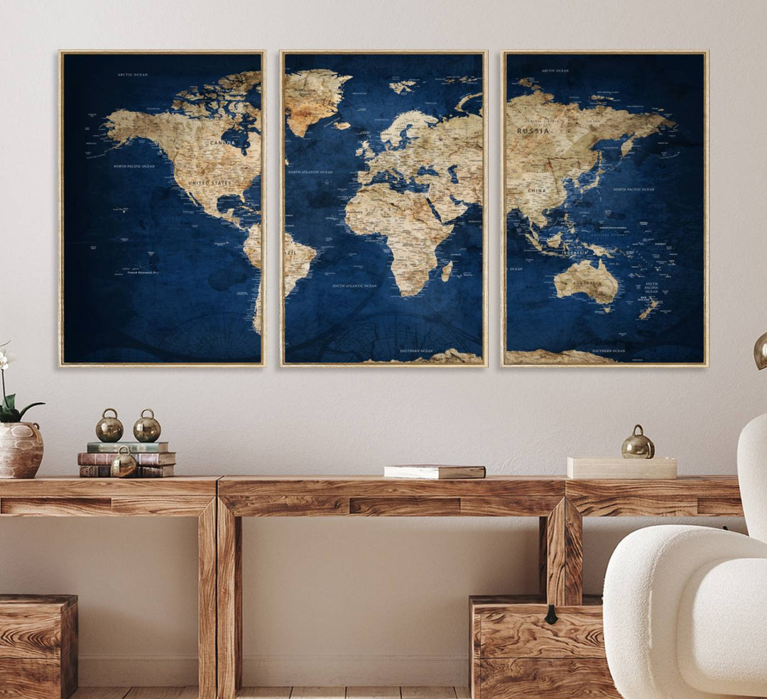 A large framed world map canvas print features beige landmasses set against a grunge-stained deep blue ocean background, creating an intriguing piece of wall art.