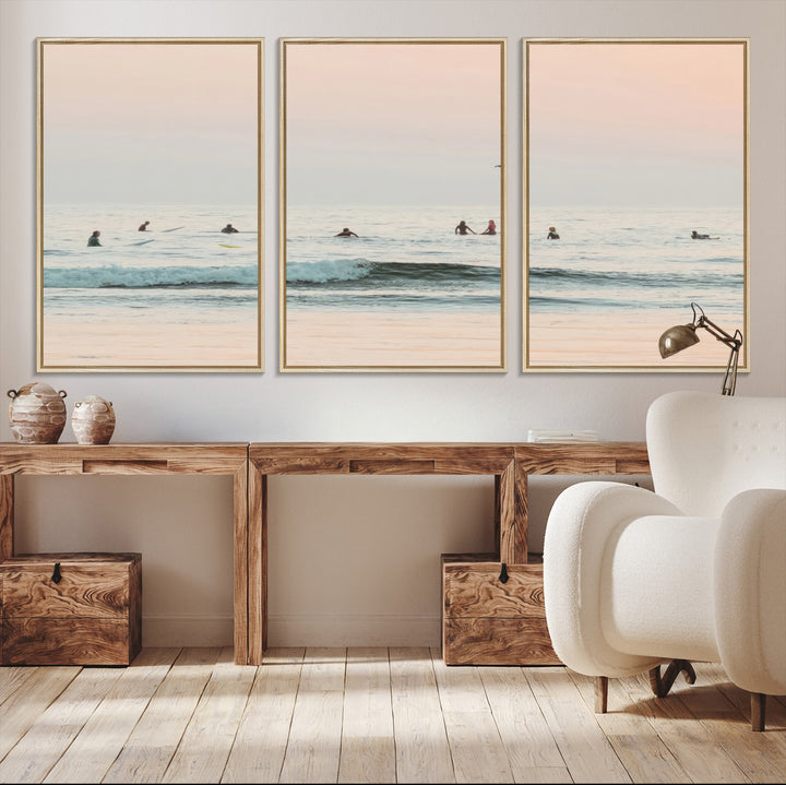 Dreamy photo of surfers waiting on soft pastel waves under a pink sunset sky, ideal for soft coastal minimalist or serene ocean-themed home decor.