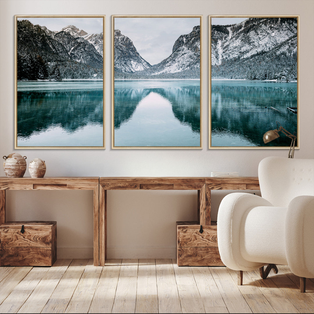 Crystal-clear alpine lake reflecting snow-covered mountains, surrounded by evergreen trees, creating a serene and tranquil winter landscape.