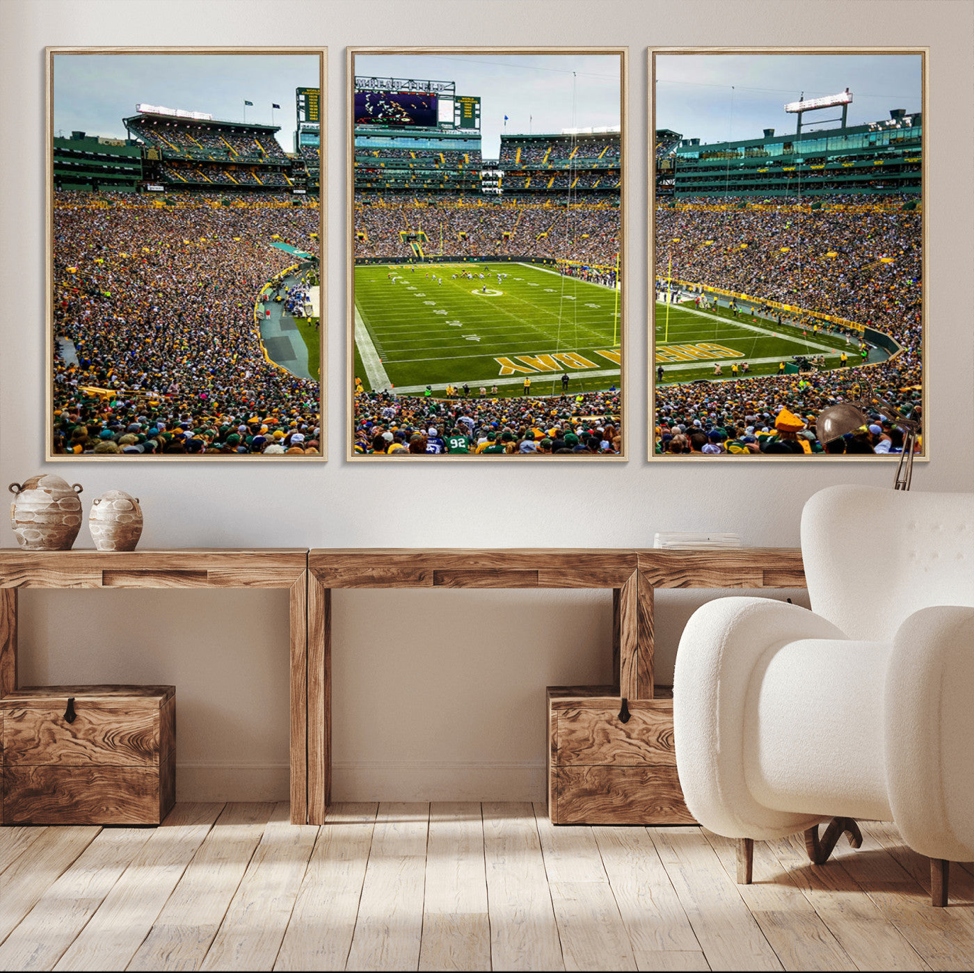 Packed football stadium with thousands of fans watching an American football game on a well-maintained field. The scoreboard displays "Lambeau Field," and players are lined up on the field. The stadium is surrounded by multiple tiers of seating filled wit