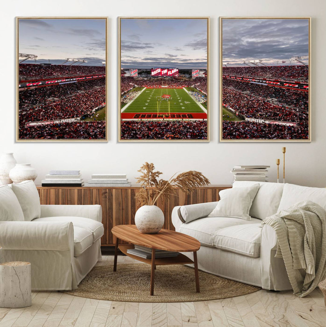 The wall art captures a stunning scene of Raymond James Stadium bathed in the warm hues of sunset. The sky, filled with clouds, provides a dramatic contrast to the vibrant lighting on the field, encapsulating the dynamic energy of a football game.