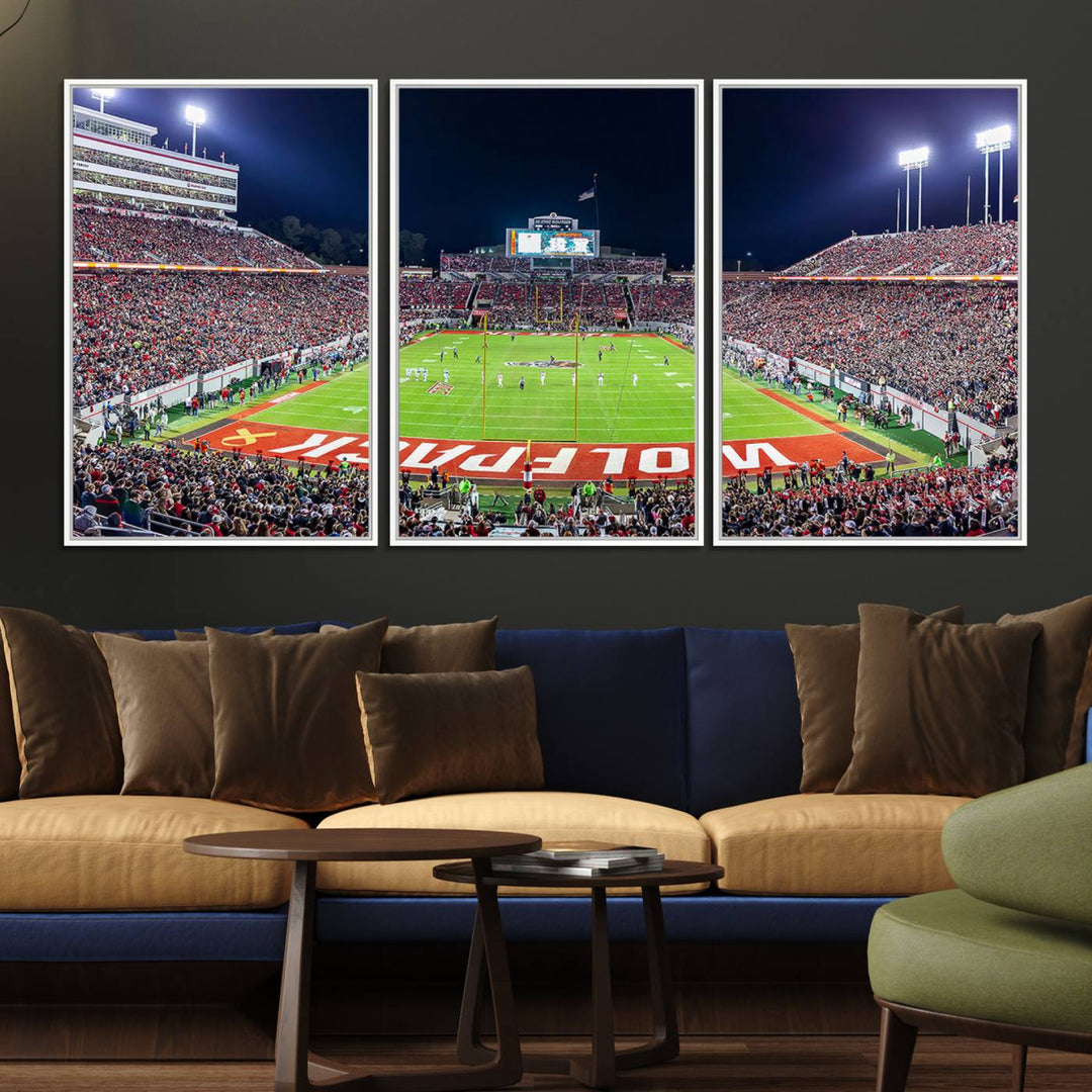 A NC State Wolfpack Football Team print of Carter-Finley Stadium at night features WOLFPACK illuminated brightly in the end zone grass.