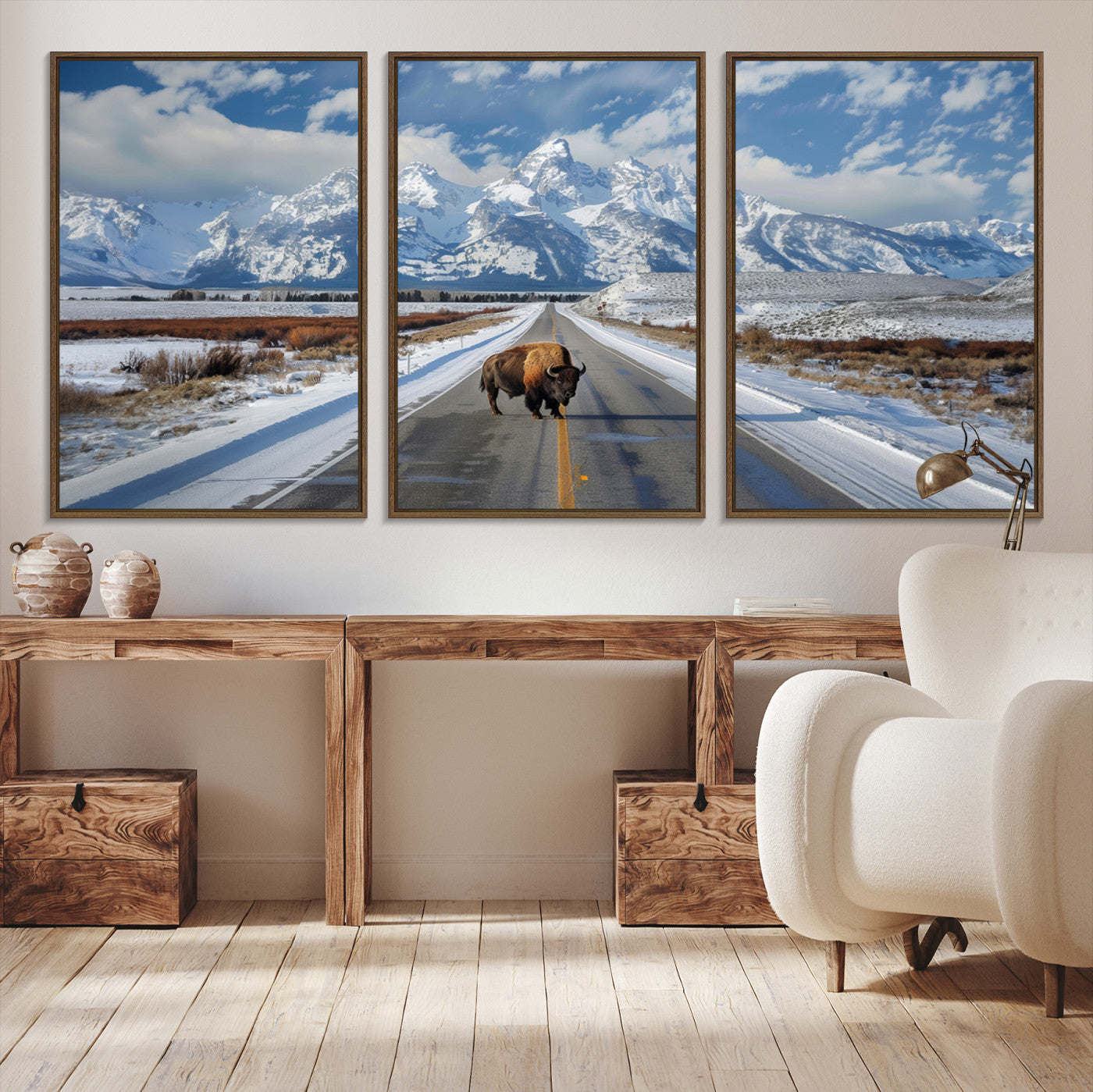 A powerful bison stands on a snow-dusted road beneath the towering peaks of the Grand Tetons, capturing the untamed beauty of America's winter wilderness.