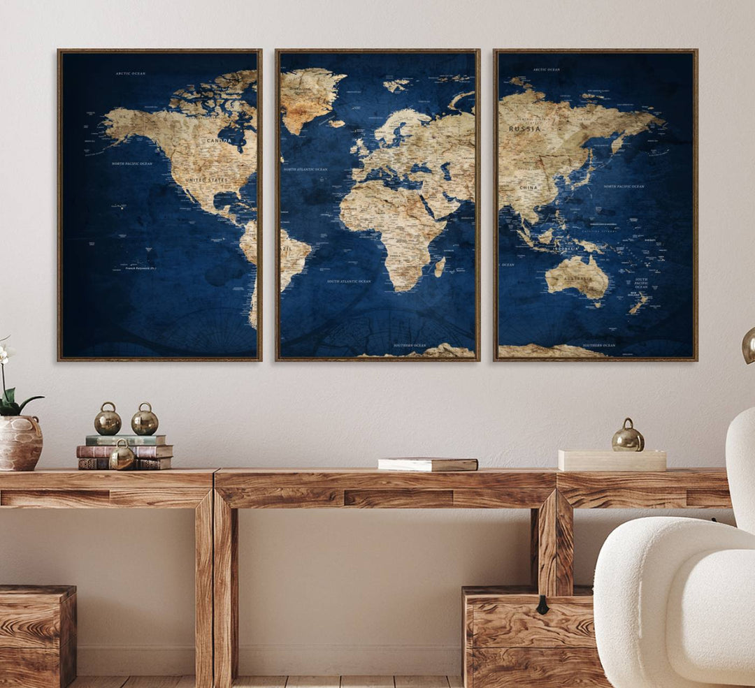 A large framed world map canvas print features beige landmasses set against a grunge-stained deep blue ocean background, creating an intriguing piece of wall art.