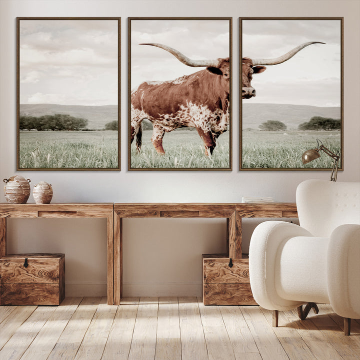 Canvas of a Texas longhorn standing in a grassy field with mountains in the background, ideal for rustic or country-style western wall decor.
