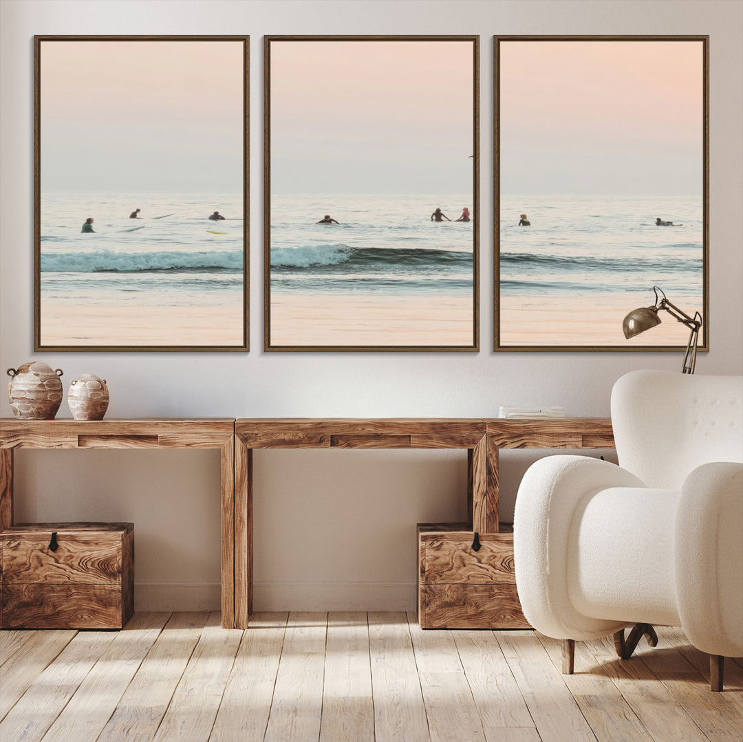 Dreamy photo of surfers waiting on soft pastel waves under a pink sunset sky, ideal for soft coastal minimalist or serene ocean-themed home decor.