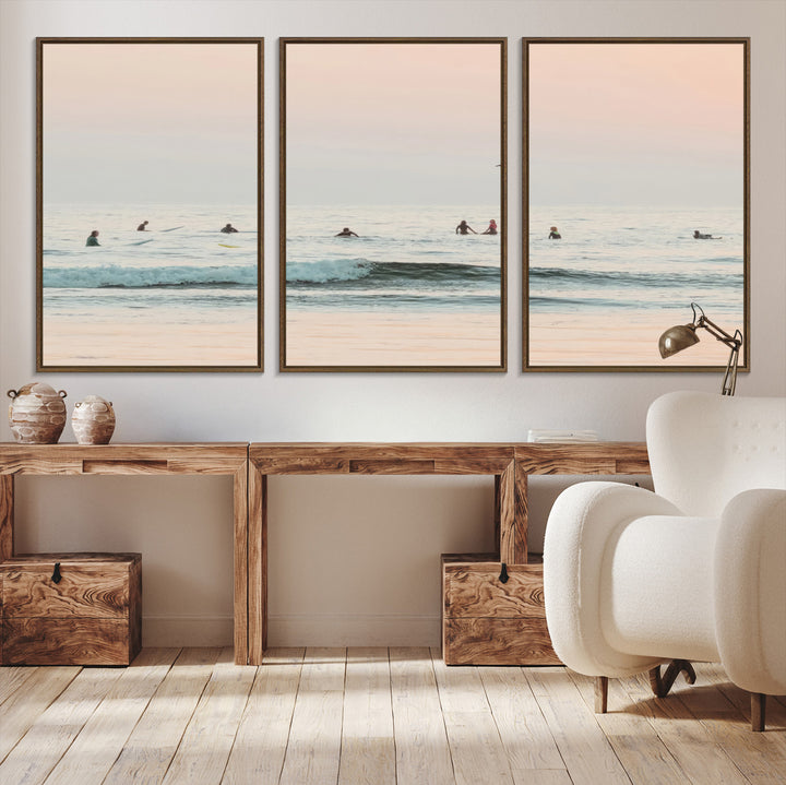 Dreamy photo of surfers waiting on soft pastel waves under a pink sunset sky, ideal for soft coastal minimalist or serene ocean-themed home decor.