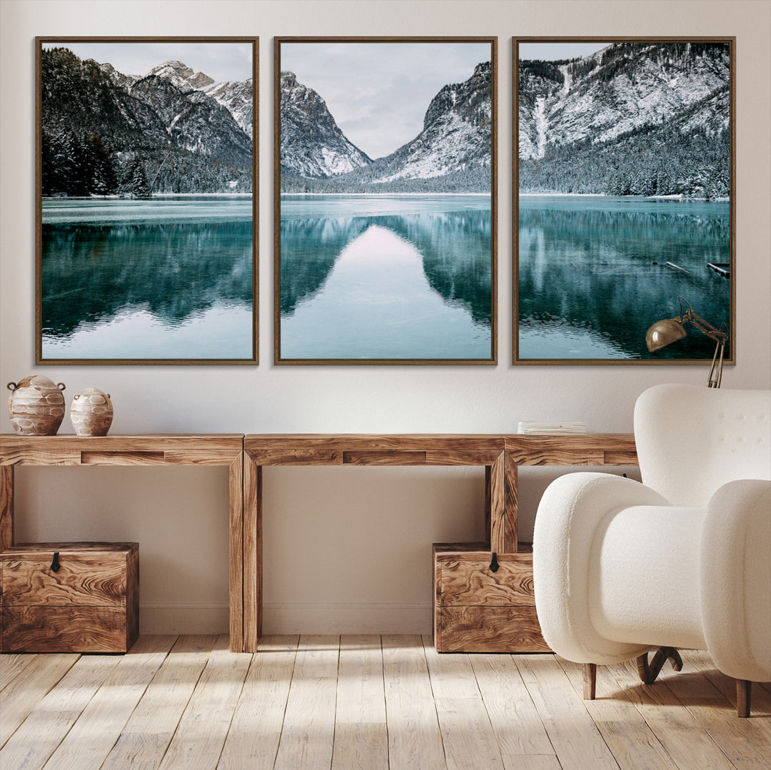 Crystal-clear alpine lake reflecting snow-covered mountains, surrounded by evergreen trees, creating a serene and tranquil winter landscape.