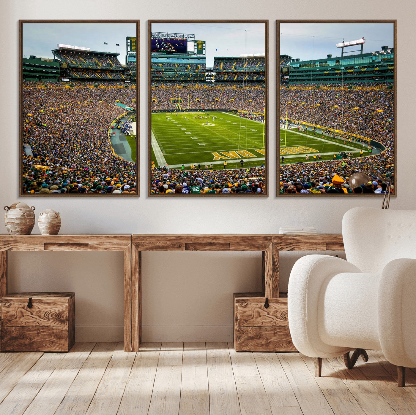 Packed football stadium with thousands of fans watching an American football game on a well-maintained field. The scoreboard displays "Lambeau Field," and players are lined up on the field. The stadium is surrounded by multiple tiers of seating filled wit