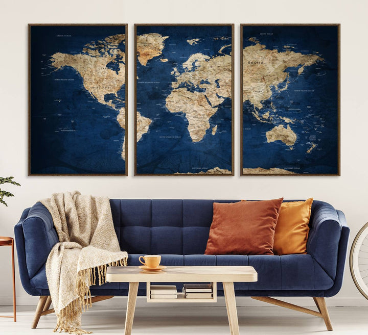 A large framed world map canvas print features beige landmasses set against a grunge-stained deep blue ocean background, creating an intriguing piece of wall art.